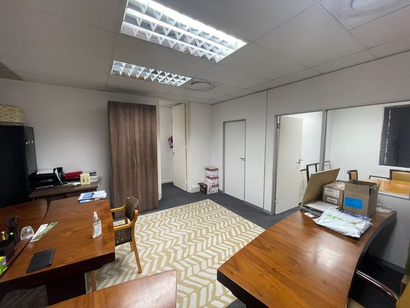 A functional office space featuring suspended ceilings, recessed lighting, and carpeted flooring, providing a practical environment for professional work.