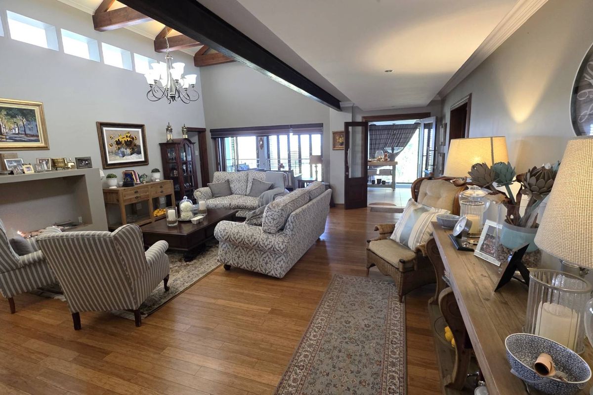 Spacious living room featuring hardwood flooring, exposed timber ceiling beams, a fireplace, and clerestory windows that provide ample natural light.