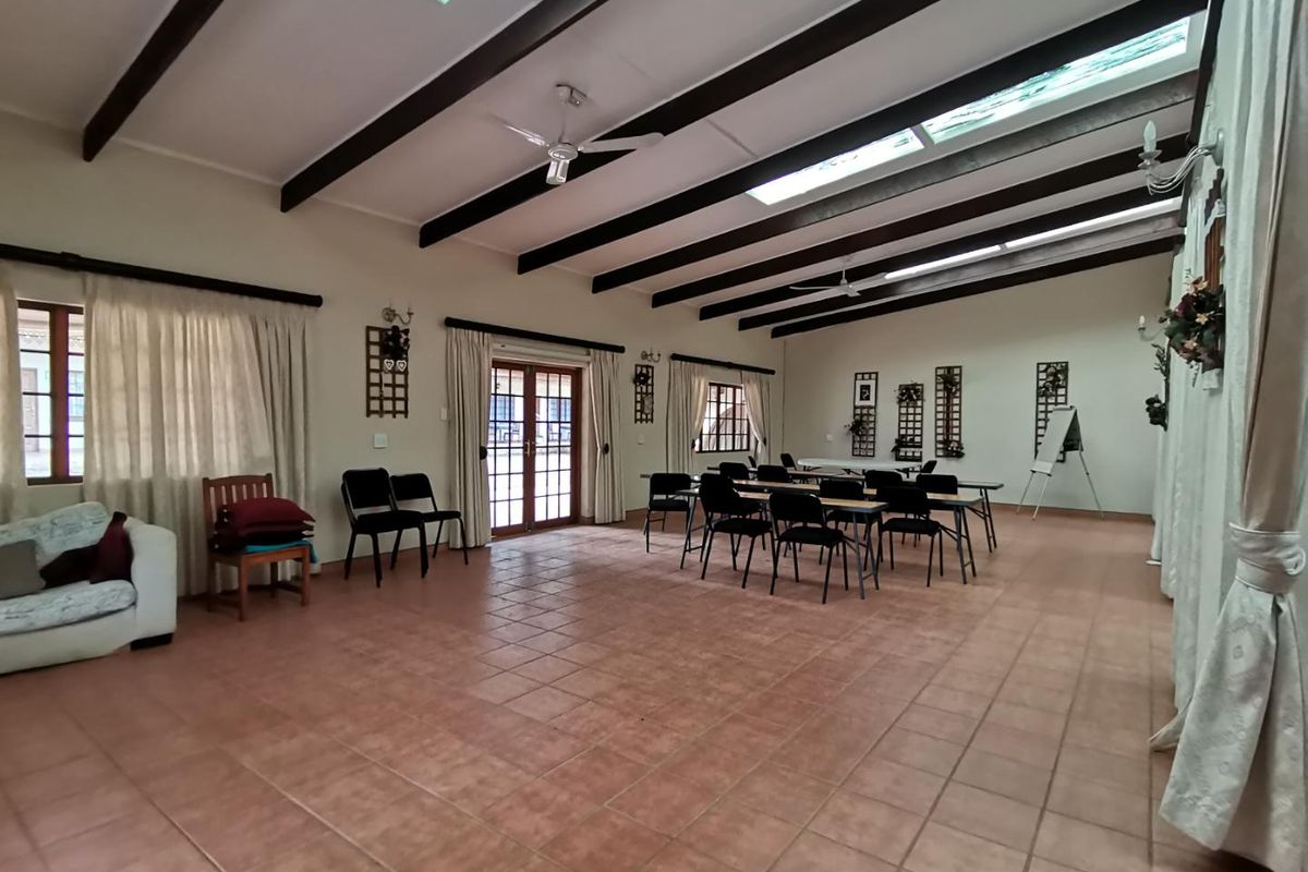 Spacious living area featuring exposed timber ceiling beams, multiple skylights, tiled flooring, and double glass doors providing natural light and access to the exterior.
