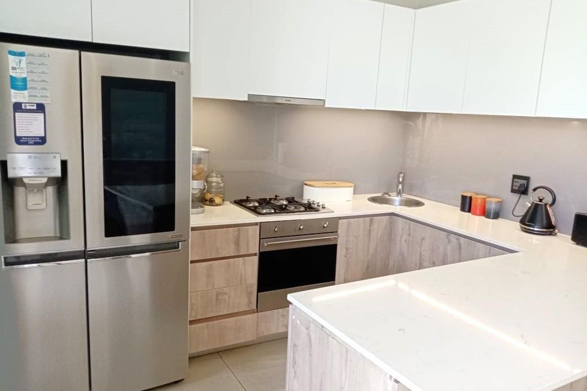 Modern kitchen featuring white upper cabinets, wood-look lower cabinetry, stone countertops, gas cooktop, built-in oven, and an undermount sink.