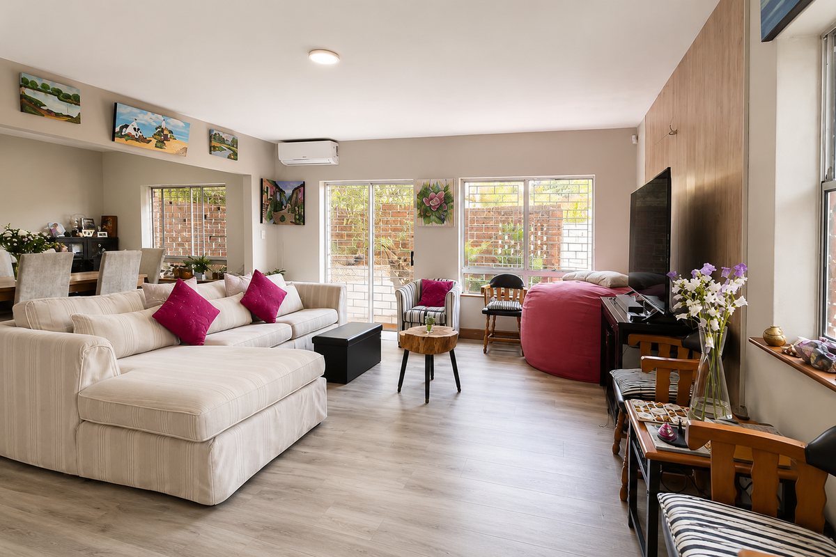 A bright and spacious living room featuring laminate flooring, split-system air conditioning, and large sliding glass doors providing access to the exterior.