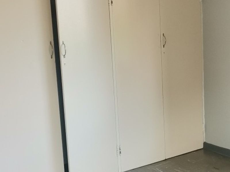 An empty bedroom featuring built-in cupboards and vinyl flooring, requiring minor repairs and cosmetic updates to improve its overall condition.