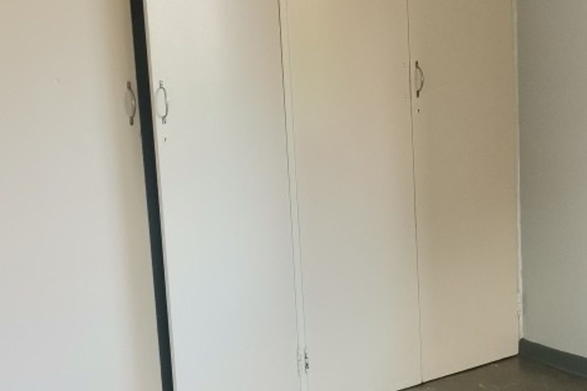 An empty bedroom featuring built-in cupboards and vinyl flooring, requiring minor repairs and cosmetic updates to improve its overall condition.