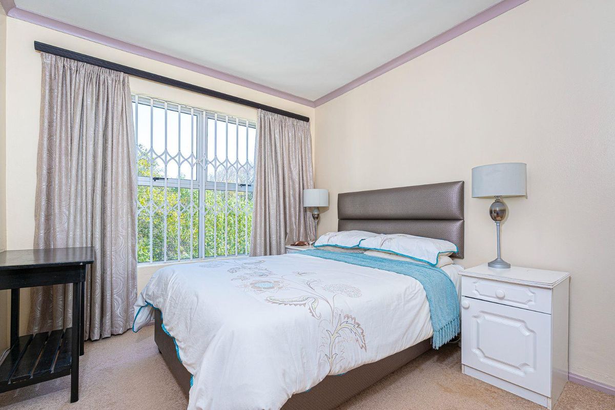 A bedroom featuring a window with integrated security bars, neutral wall finishes, and carpeted flooring.