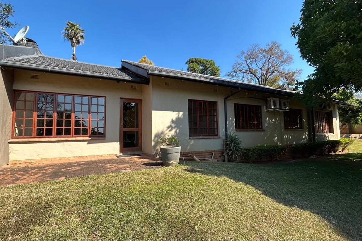 Rear view of the house featuring a paved patio area, established lawn, and traditional timber-framed windows under a tiled roof.
