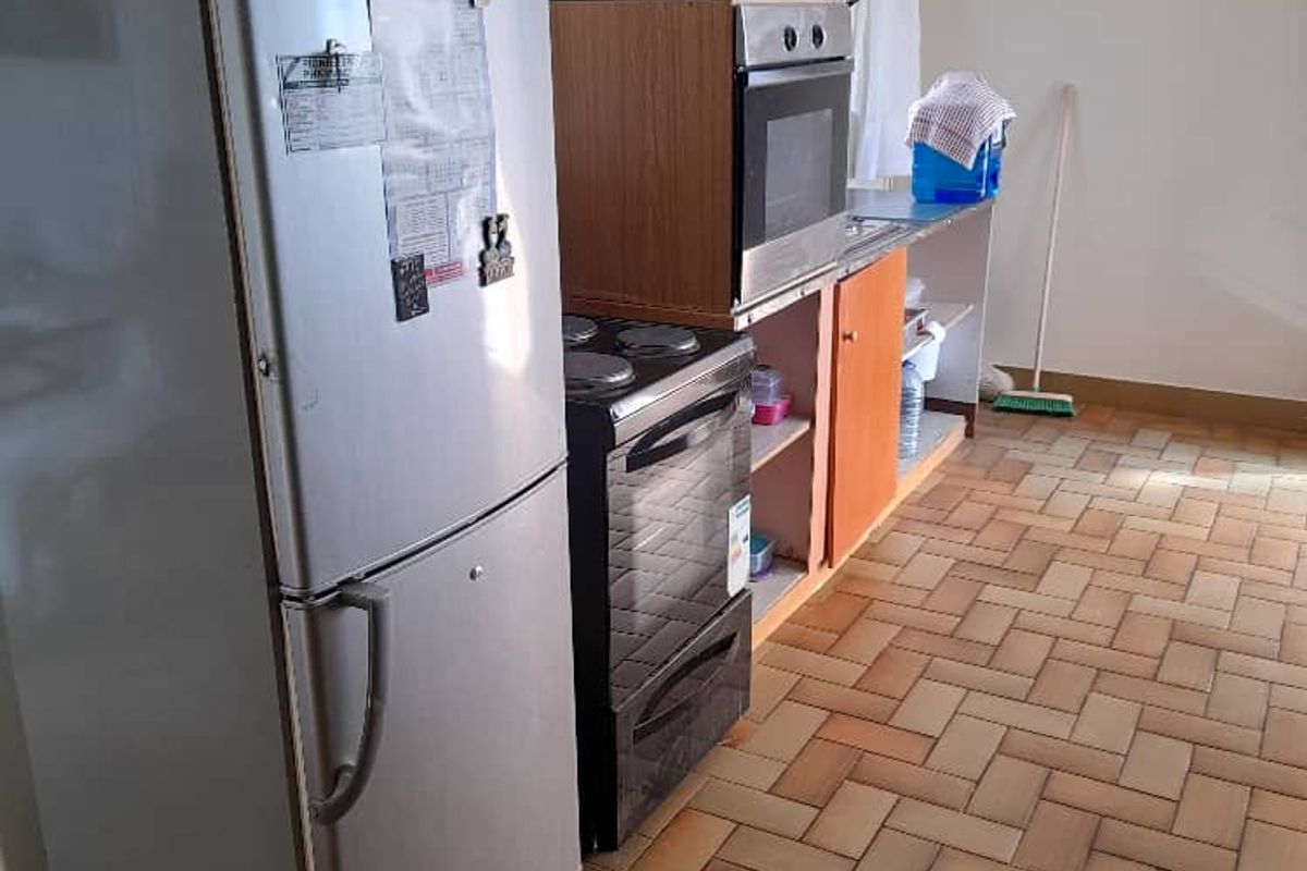 A functional kitchen area featuring tiled flooring, built-in cabinetry, and integrated oven and hob cooking appliances.