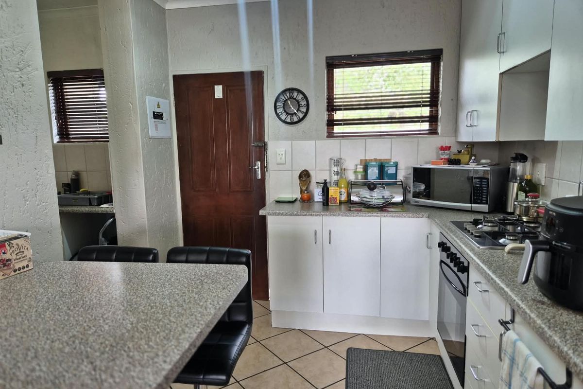 A functional kitchen featuring built-in cabinetry, granite countertops, a gas hob, and an integrated oven, with tiled flooring and natural light.