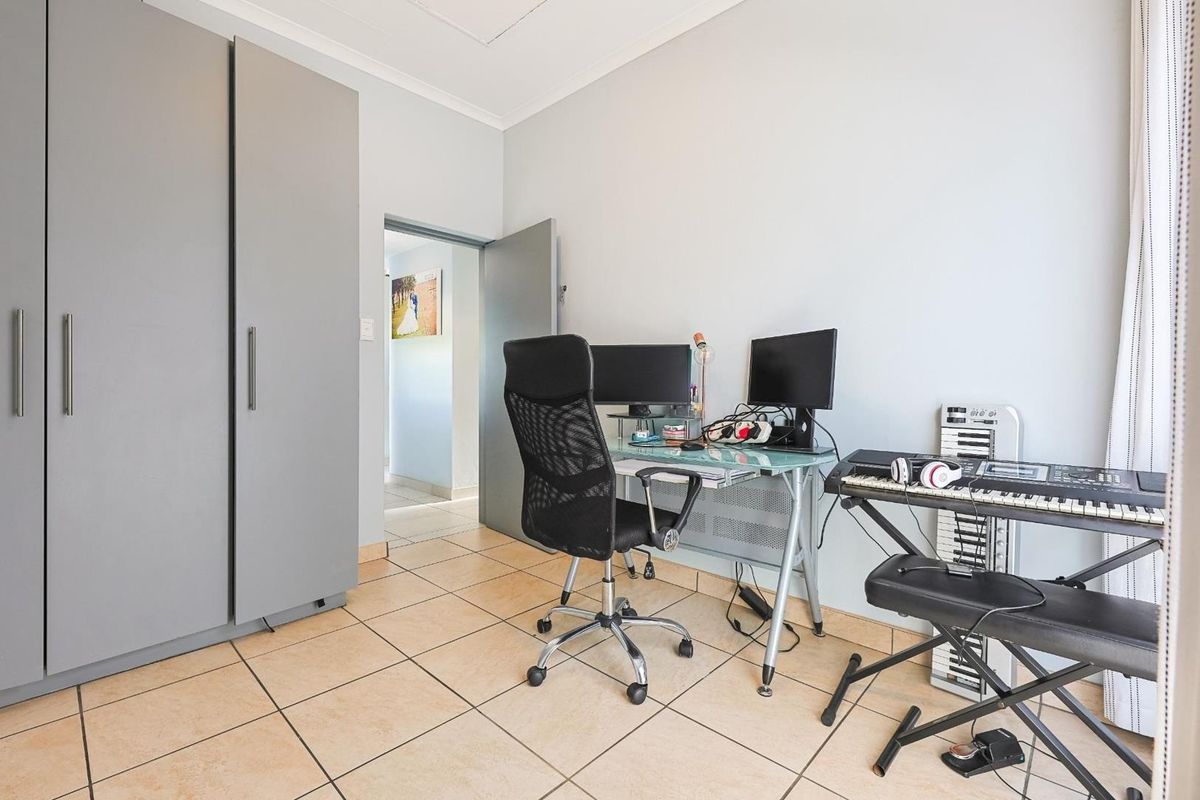 A functional bedroom or home office space featuring built-in grey cabinetry and tiled flooring, providing a versatile area for work or rest.