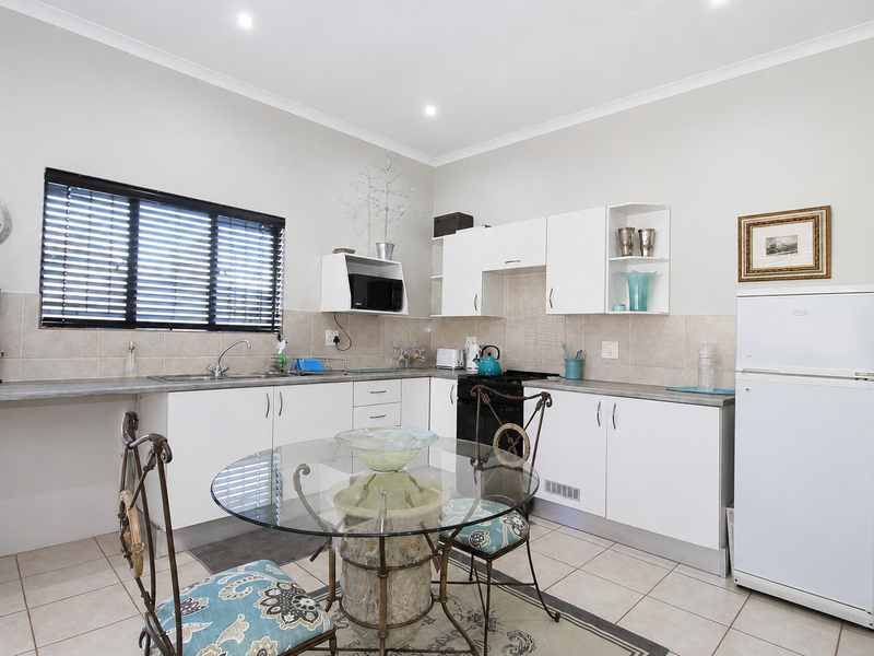 A functional kitchen featuring white cabinetry, laminate countertops, tiled backsplash, and ceramic floor tiles, offering a clean and practical workspace.
