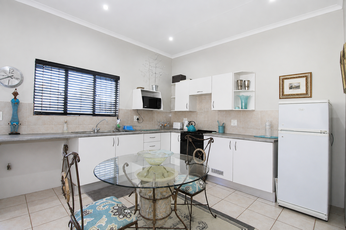 A functional kitchen featuring white cabinetry, laminate countertops, tiled backsplash, and ceramic floor tiles, offering a clean and practical workspace.
