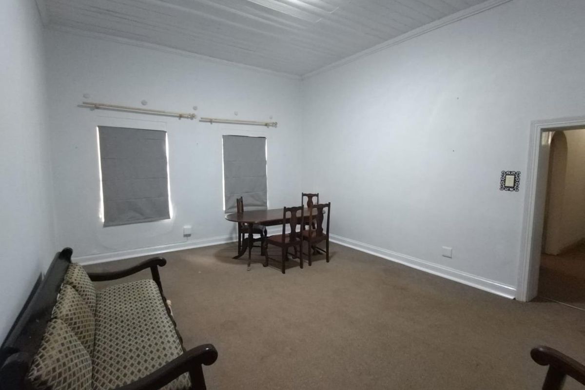 A spacious living area featuring a timber ceiling, carpeted flooring, and dual windows with fitted roman blinds.