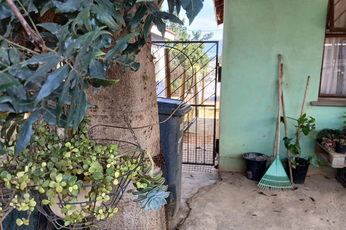A side or rear exterior area featuring a metal security gate, concrete paving, and a painted wall surface.