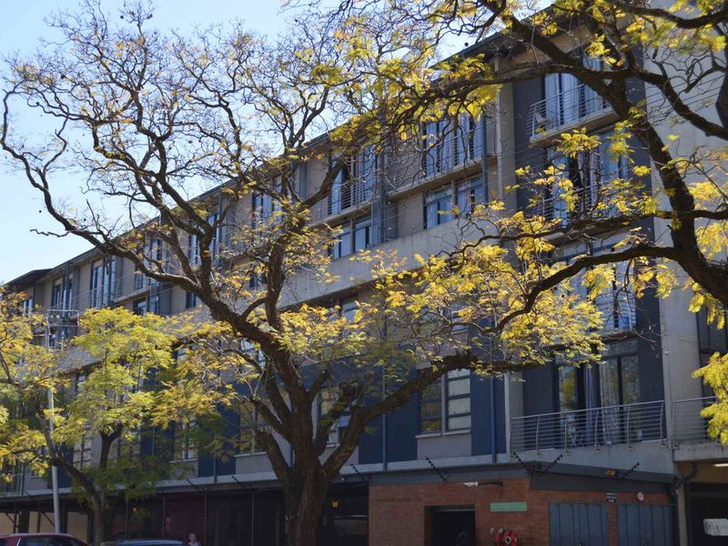 A multi-story apartment building facade featuring modern architectural design with balconies, large windows, and a combination of brick and concrete finishes.