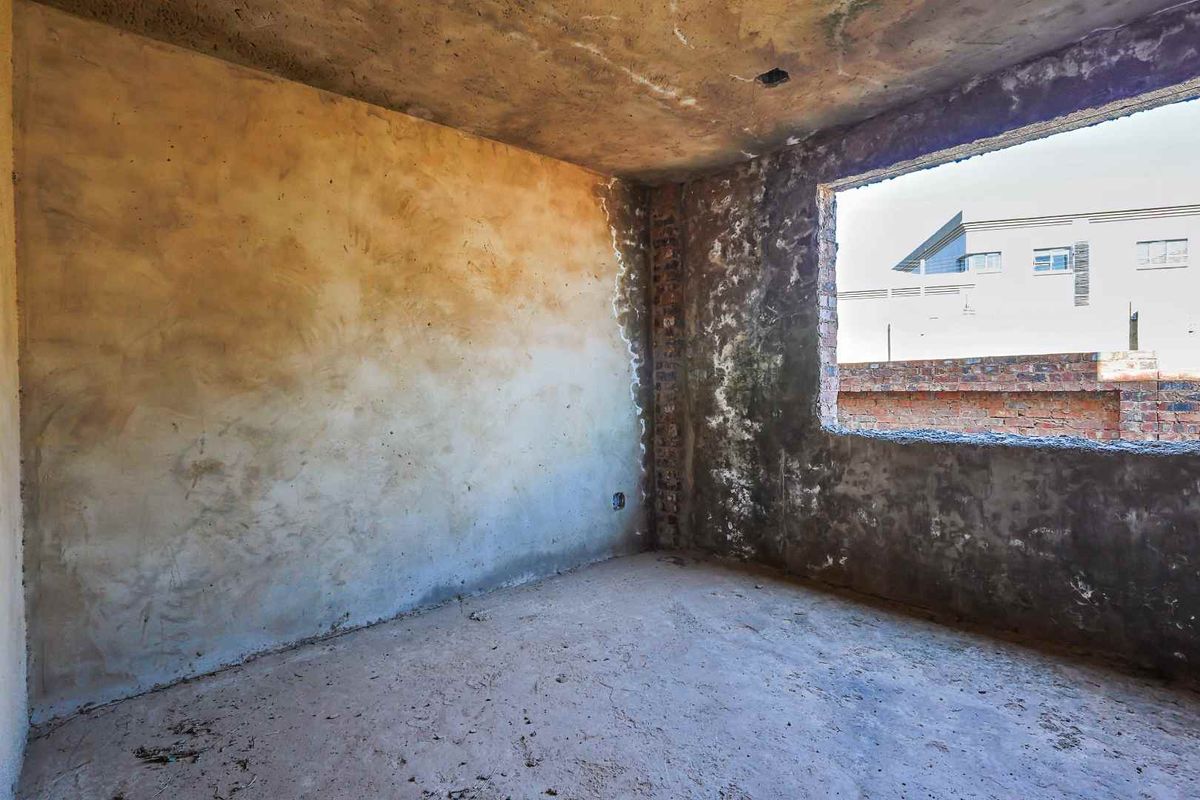 An unfinished bedroom interior featuring raw concrete walls, exposed brickwork, and an open window aperture, requiring significant renovation and finishing work.