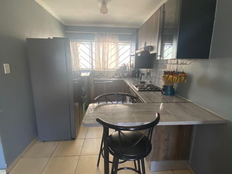 Compact kitchen featuring built-in cabinetry, laminate countertops, a hob with extractor fan, and ceramic floor tiles.