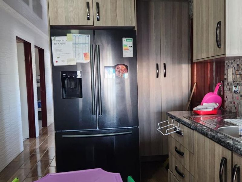 A functional kitchen featuring wood-look cabinetry, granite countertops, and tiled flooring, providing a practical workspace with integrated storage solutions.
