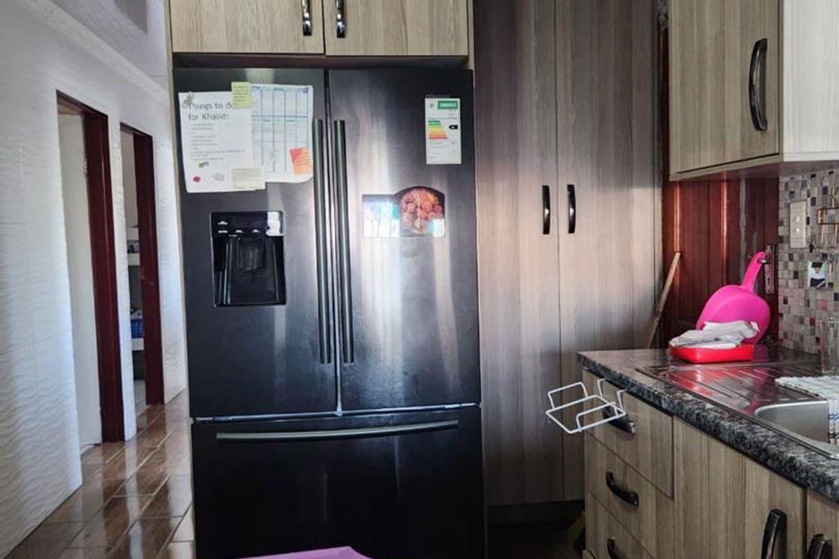 A functional kitchen featuring wood-look cabinetry, granite countertops, and tiled flooring, providing a practical workspace with integrated storage solutions.