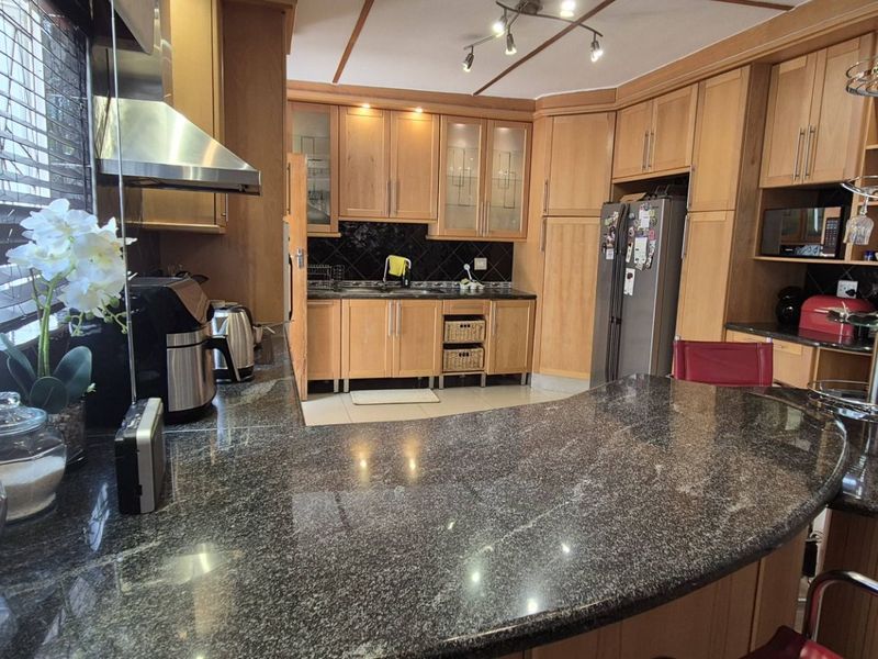 A functional kitchen featuring wooden cabinetry, granite countertops, and a breakfast bar, offering ample storage and workspace for daily meal preparation.