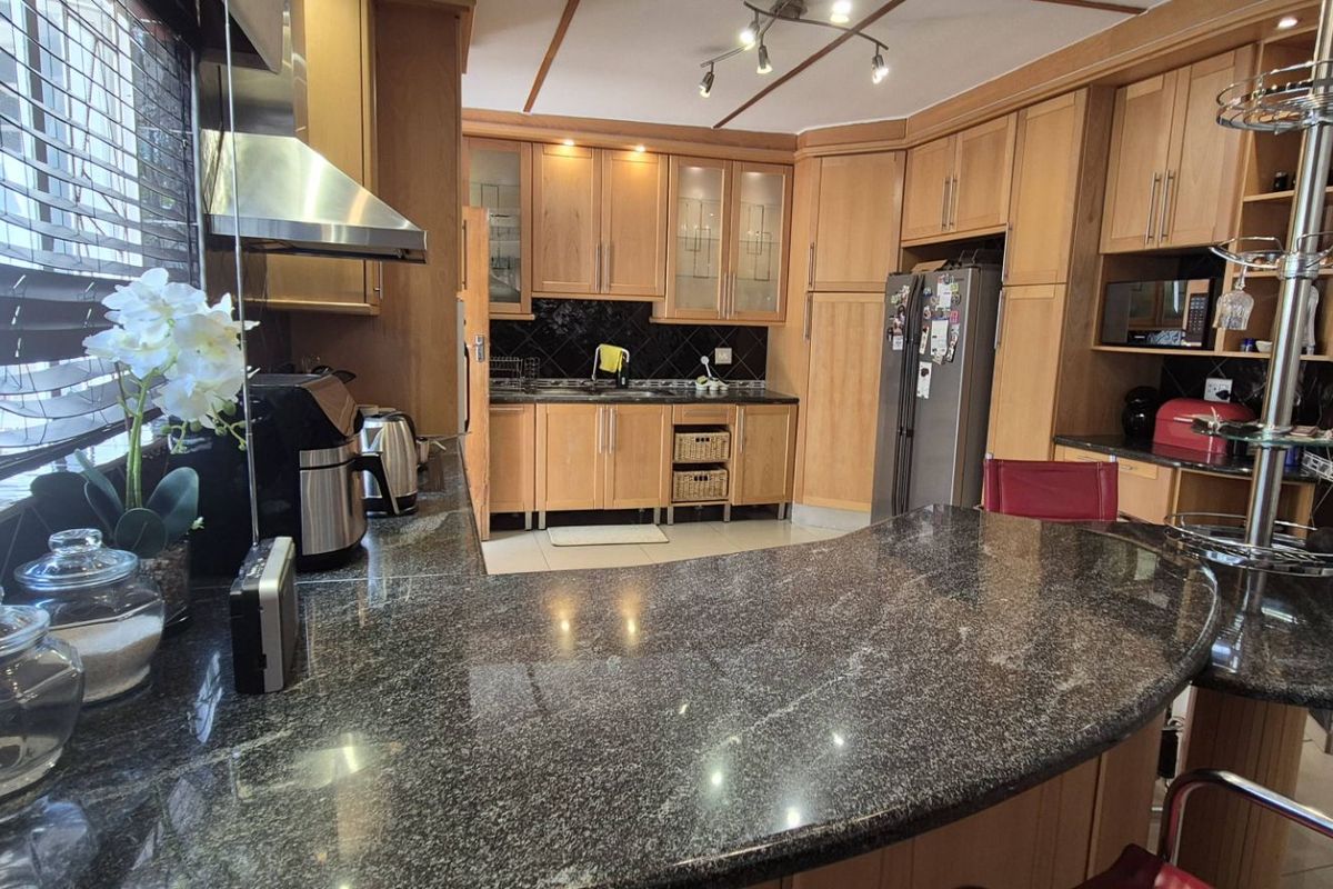 A functional kitchen featuring wooden cabinetry, granite countertops, and a breakfast bar, offering ample storage and workspace for daily meal preparation.