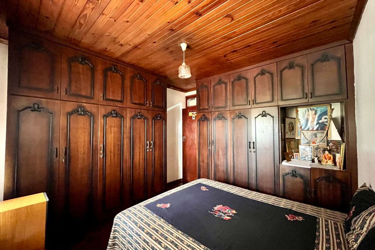 A bedroom featuring extensive floor-to-ceiling built-in wooden cabinetry and traditional timber ceiling paneling, offering significant storage space.