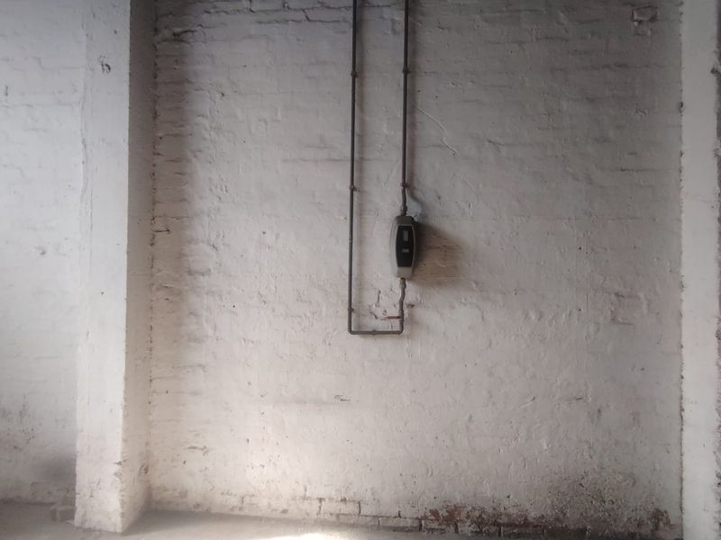 Industrial utility space featuring exposed white-painted brick walls and surface-mounted utility piping and meter.