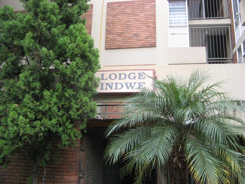 Front facade of Lodge Indwe apartment building featuring brickwork detailing and security window bars.
