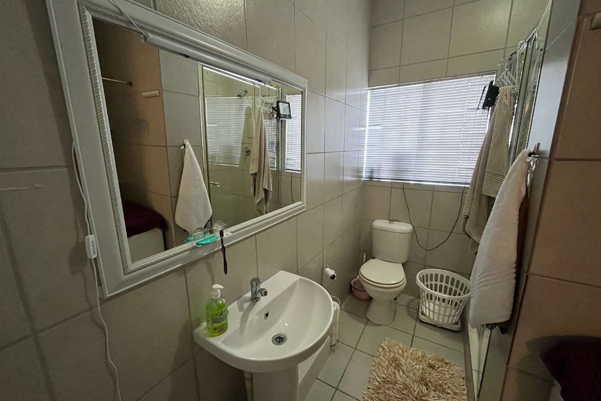 A functional bathroom featuring a pedestal sink, toilet, and full-height wall tiling, providing a practical and clean space.