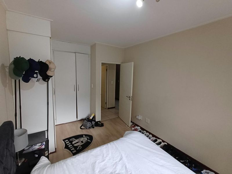 A standard bedroom featuring light-toned laminate flooring and a built-in wardrobe with white doors.