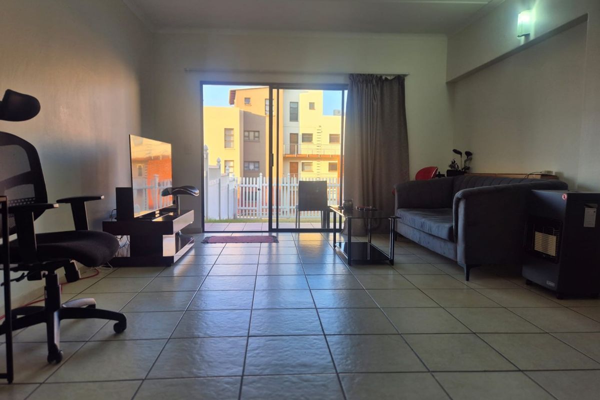 A living room featuring ceramic floor tiles and a large sliding glass door providing access to an outdoor area.