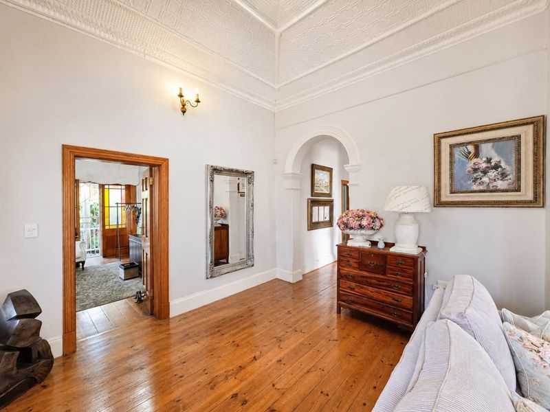 A well-maintained living room featuring original pressed metal ceilings, polished timber flooring, and a classic architectural archway leading to adjacent spaces.