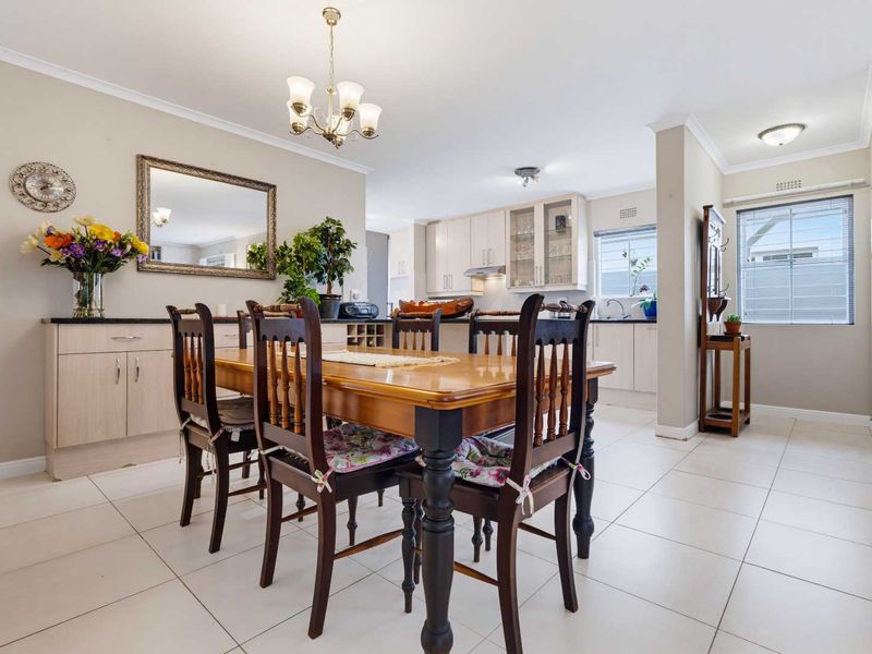 Open-plan dining and kitchen area featuring tiled flooring, built-in cabinetry, and a classic chandelier, creating a functional and connected living space.
