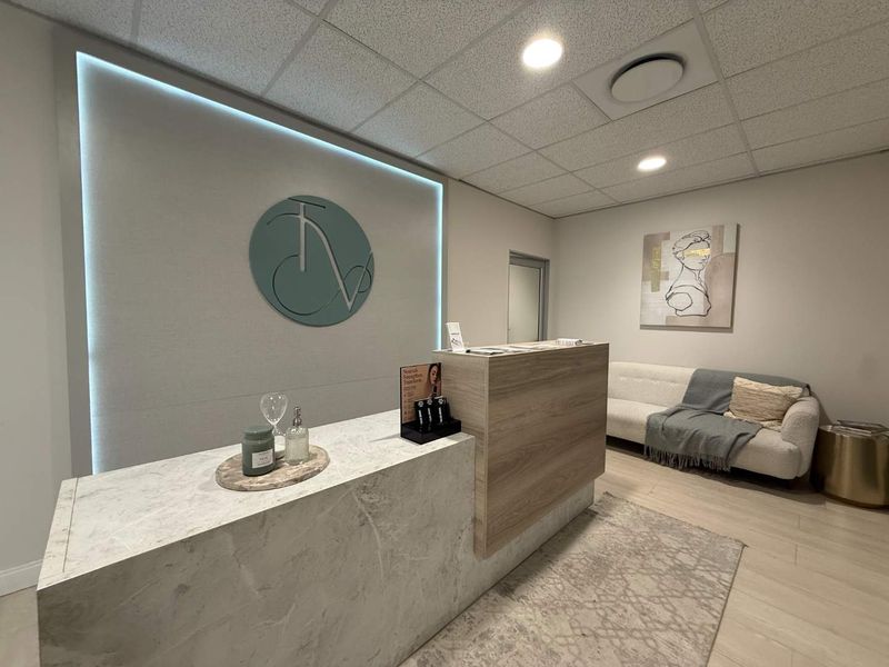 Modern office reception area featuring a marble-look reception desk, backlit feature wall, and professional drop ceiling lighting.