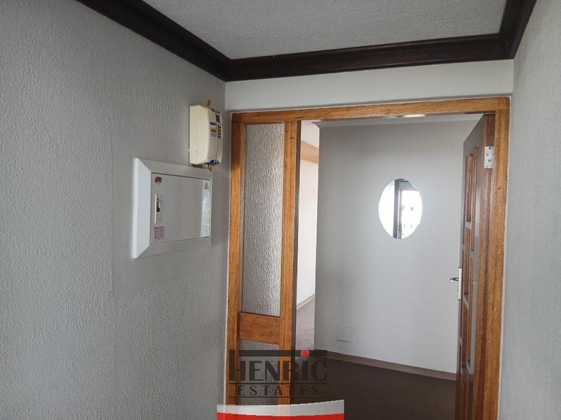 A functional hallway featuring a timber door frame with textured glass and a circular window, providing access to an adjacent room.