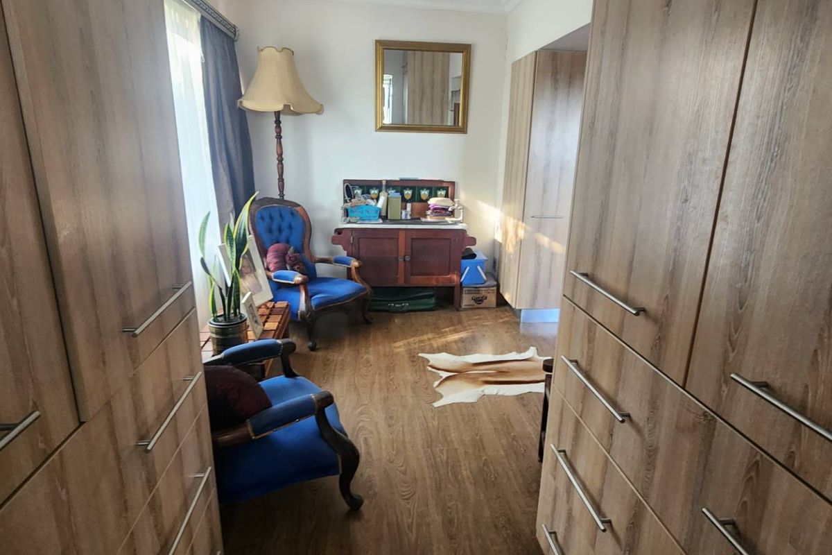 A bedroom featuring extensive built-in wooden cabinetry and laminate flooring, providing ample storage space.
