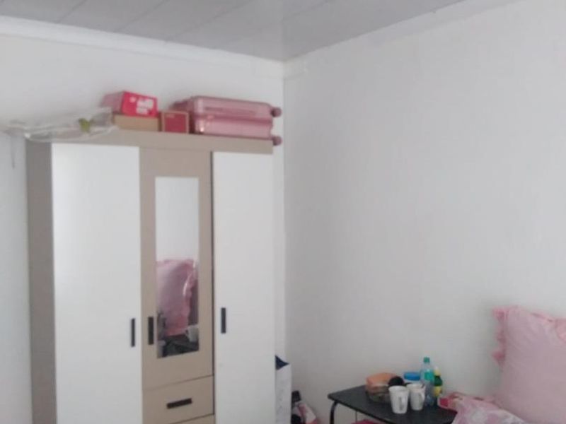 A functional bedroom featuring a built-in wardrobe and a panelled ceiling, providing basic storage and living space.
