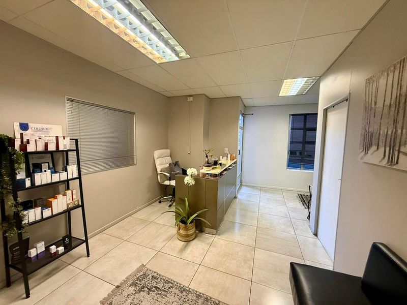 A professional office reception area featuring tiled flooring, a built-in reception desk, and suspended ceiling lighting, creating a clean and functional workspace.