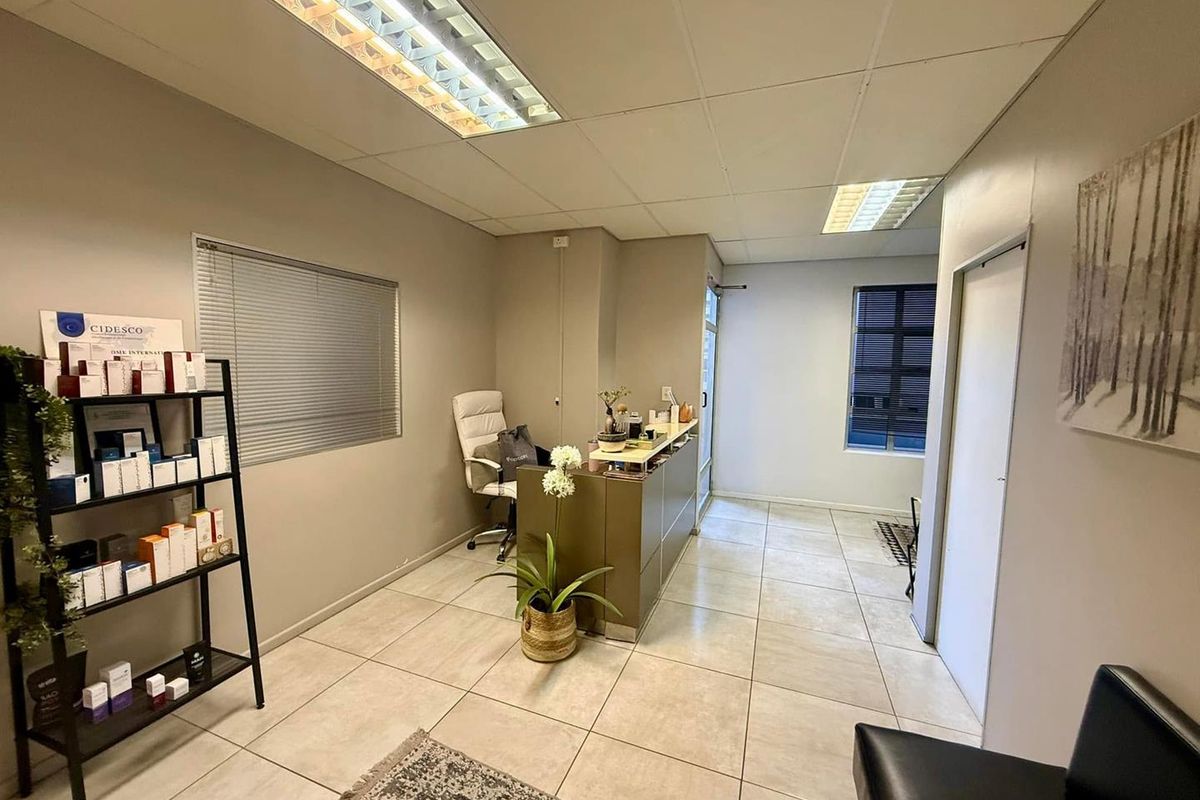 A professional office reception area featuring tiled flooring, a built-in reception desk, and suspended ceiling lighting, creating a clean and functional workspace.