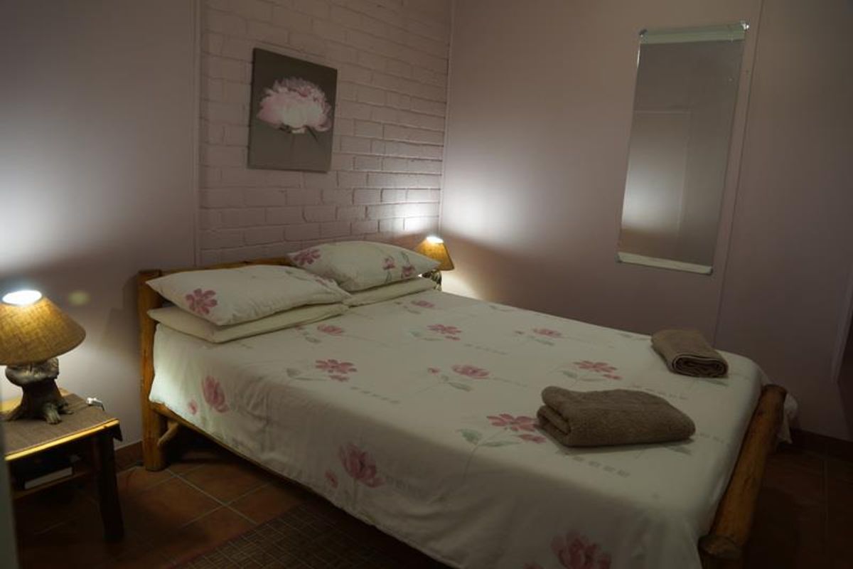 A cozy bedroom featuring a painted brick accent wall and tiled flooring.