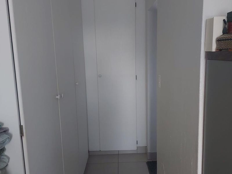 A functional hallway featuring neutral tiled flooring and ample built-in cupboard storage space.
