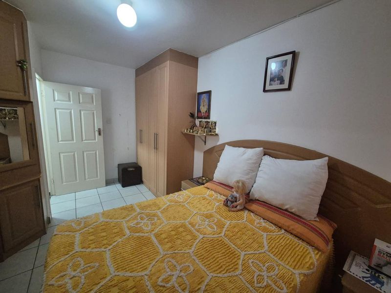 A functional bedroom featuring built-in wooden cupboards, tiled flooring, and a standard panel door.