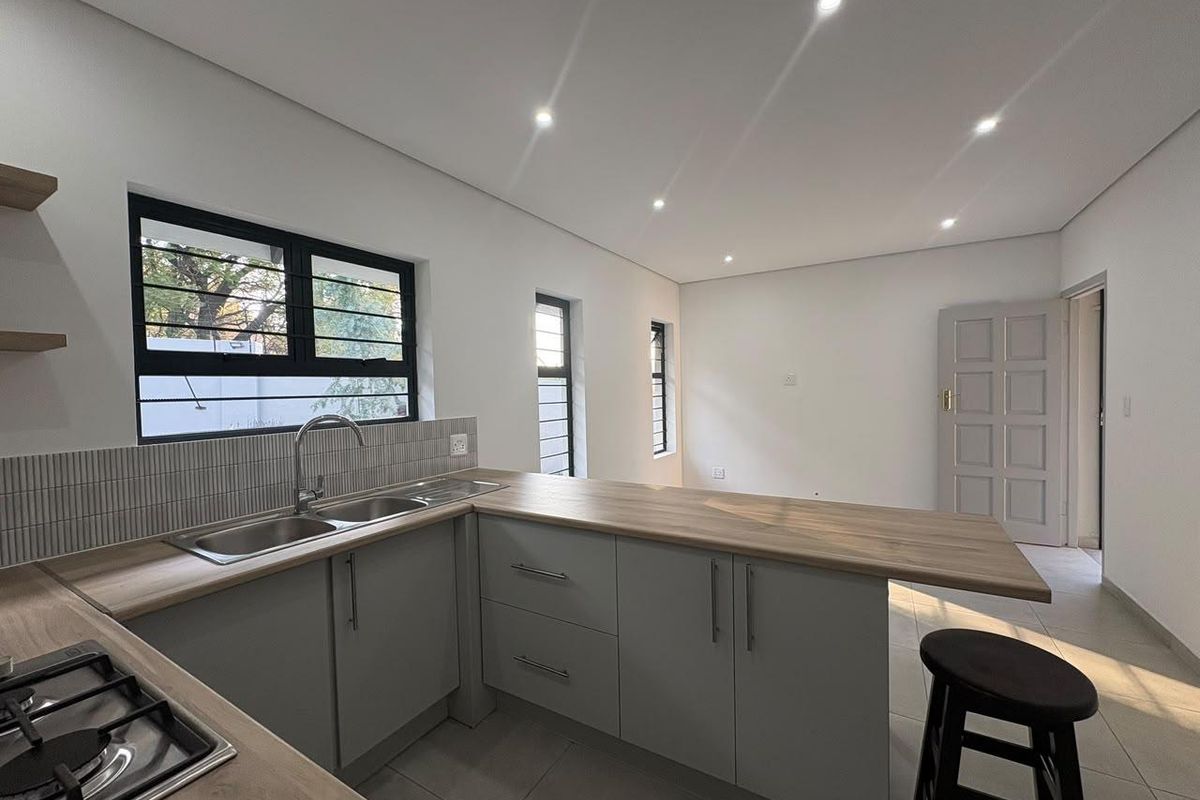 Modern kitchen featuring light grey cabinetry, wood-look laminate countertops, a gas hob, and a stainless steel double sink with tiled backsplash.