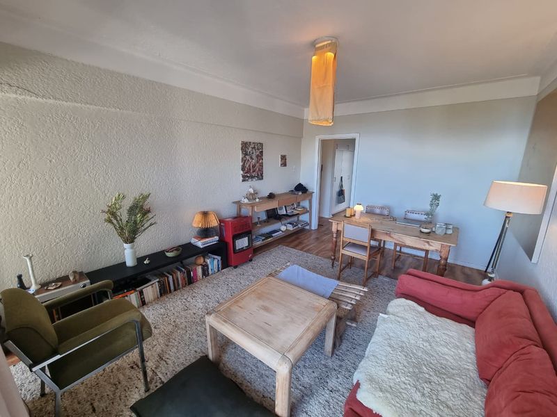 A living room featuring textured walls, coving, and laminate flooring, with visible plaster cracking on the main wall.