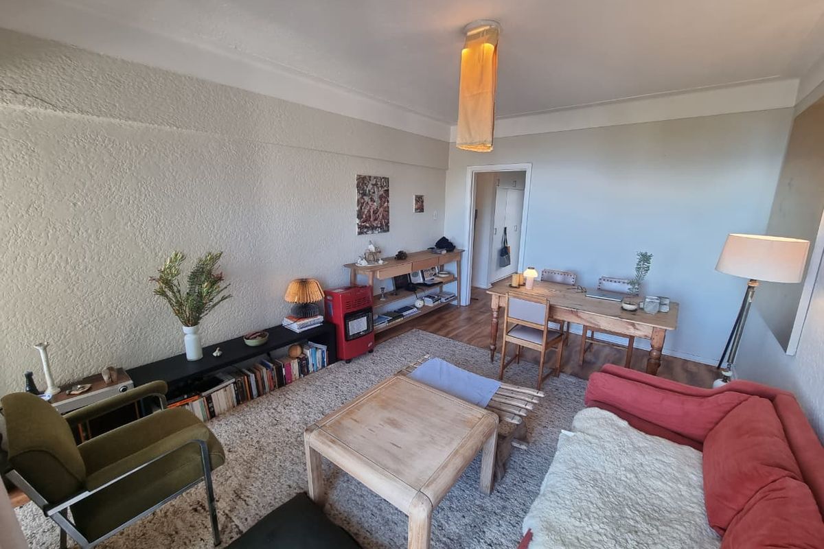 A living room featuring textured walls, coving, and laminate flooring, with visible plaster cracking on the main wall.
