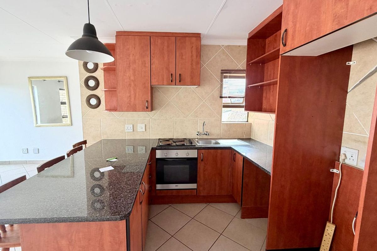 A functional kitchen featuring cherry-wood cabinetry, granite countertops, a built-in oven with hob, and a breakfast bar island.