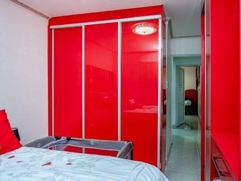 Bedroom featuring high-gloss red built-in cupboards and tiled flooring, providing ample storage space within the apartment.