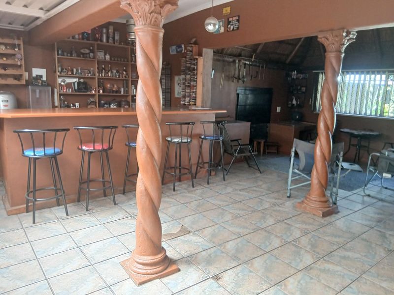 A dedicated bar area featuring a built-in counter, custom shelving, and decorative columns, finished with tiled flooring.