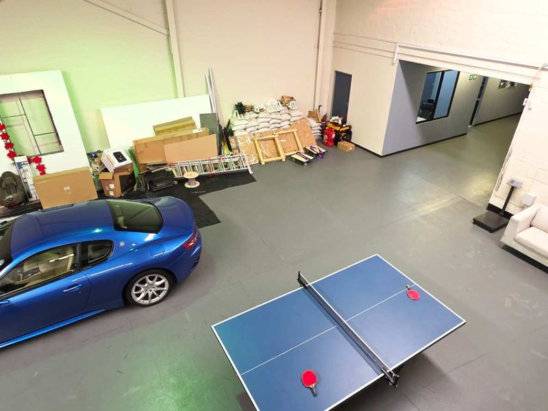 Spacious industrial utility area featuring painted concrete floors, exposed steel roof trusses, and direct access to an internal hallway.