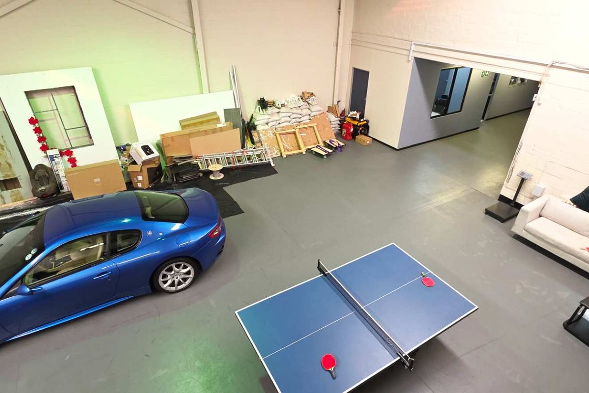 Spacious industrial utility area featuring painted concrete floors, exposed steel roof trusses, and direct access to an internal hallway.
