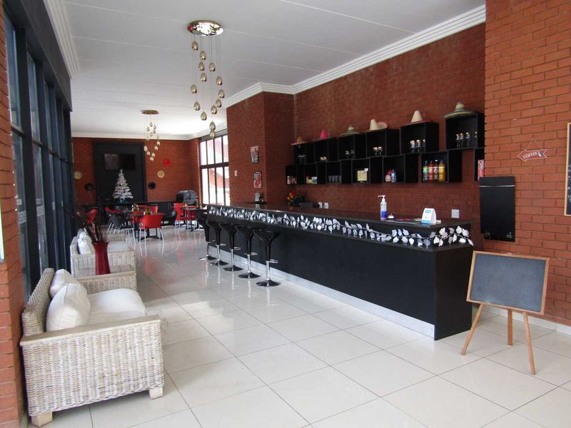 A spacious bar area featuring a long built-in counter, exposed brick walls, tiled flooring, and decorative pendant lighting.