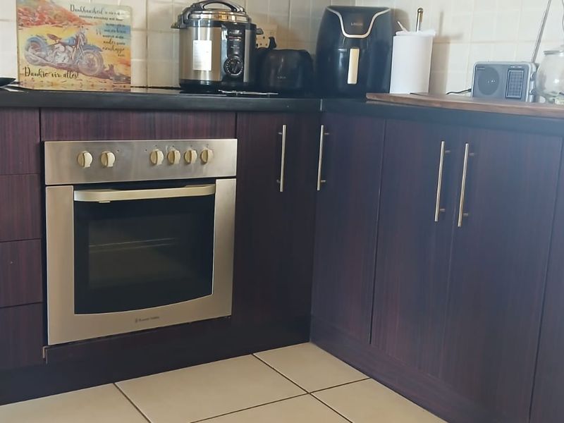A functional kitchen featuring dark wood cabinetry, a built-in oven, tiled backsplash, and tiled flooring.